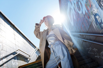 Young photo model posing outside wearing red beret and beige coat