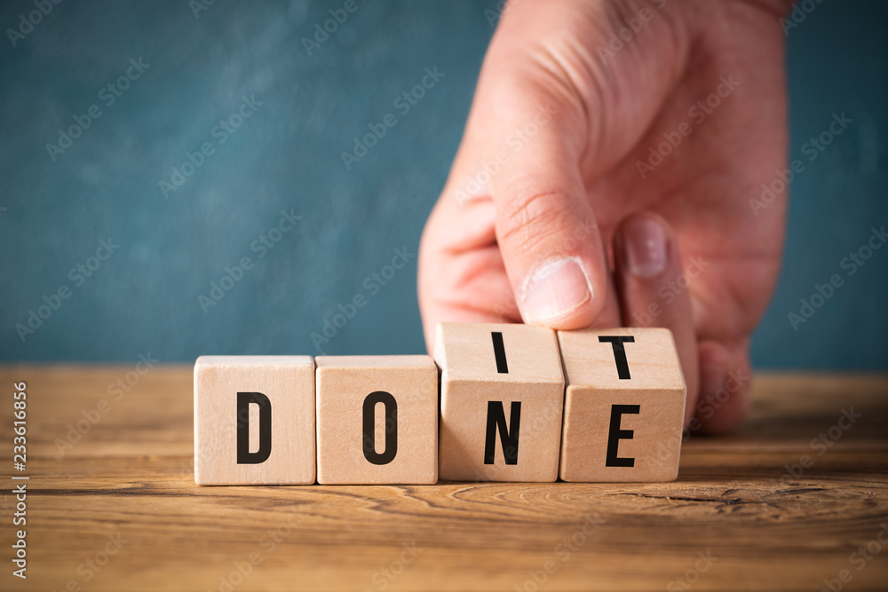 Hand turns two cubes, changing the word "do it" to "done"  - obrazy, fototapety, plakaty 