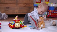 Infant Child Sitting And Playing With Toy Cat