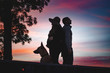© Alexander - silhouettes of a couple with dog standing back on back at sunset