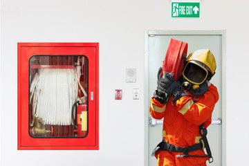 Fireman in action with a rolled fire hose and the emergency fire extinguisher equipment.