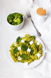 Smaczny obiad: Zielony makaron z brokułami, serem feta i sosem ziołowym na białym tle. 
