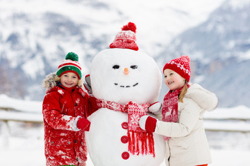 Wall Mural - Child building snowman. Kids build snow man.