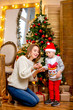 © Sergei Shavin - Happy young family, father, mother and son, in Christmas evening in home. Mom and son decorate Christmas tree. New Year's and Christmas theme. Holiday mood