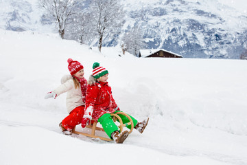 Wall Mural - Kids play in snow. Winter sleigh ride for children