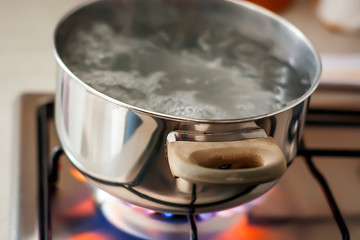 Water boiling in a pot over a lit stove