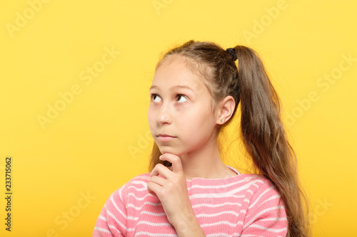 Fotografía interested thoughtful girl looking up and sideways on virtual object or text