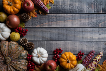 Wall Mural - top view of autumn maple leaves with pumpkin, apple, corn and red berries on old wooden background. 