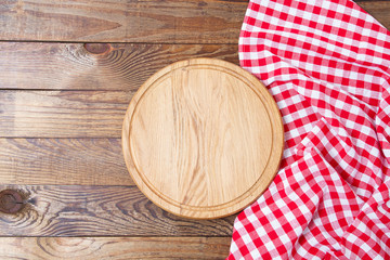 Wall Mural - Brown old vintage wooden table with framed red checkered tablecloth and pizza cutting board.Thanksgiving day and Cristmas table concept. Top view and copy space. Selective focus