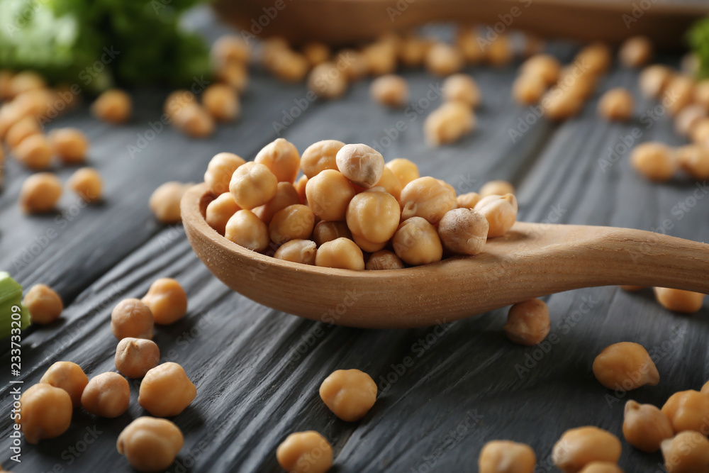 Spoon with chickpeas on wooden table