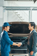 Auto mechanic shaking hands with car owner after repaired the car in auto salon
