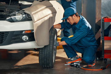 Wall Mural - Car mechanic changing a wheel of a modern car in auto service