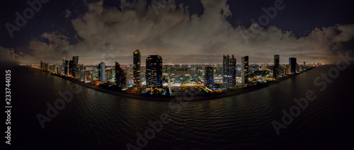 Cuadros en Lienzo Aerial night drone panoramac photo coastal city highrise tower illuminated
