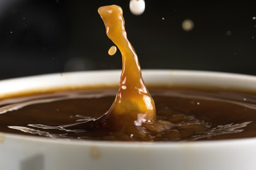 Beautiful bursts of milk drops on the surface of the coffee closeup