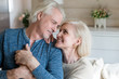 © fizkes - Portrait of happy sensual senior couple looking in eyes holding hands posing for family picture, smiling romantic aged husband and wife hugging expressing love and support shooting at home together