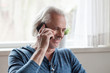 © fizkes - Happy aged man talk over phone with beloved sitting at home, senior male smile speaking on smartphone, having casual conversation, elderly gentleman or husband having fun communicating on cell