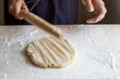 © Andrew Scrivani - Close up of man beating dough with rolling pin
