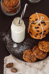 Glass with fresh milk and homemade chocolate chips cookies over a dark table. 