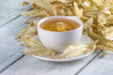 white cup linden tea or blooming tilia, basswood, on rustic vintage white wooden table. Herbal tea concept, selective focus