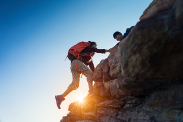 Young asian couple climbing up on the mountain,hiking and team work concept.