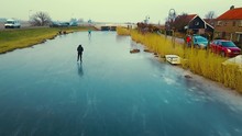Drone Shot Of A Boy Ice Skating In A Typical Dutch Landscape With Windmills In The Background