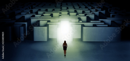 Fotografía Lost woman standing at the dark labyrinth with illuminated door