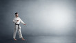 © ra2 studio - Small karate man fighting in an empty grey copy space