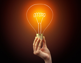 Hand holding light bulb on dark background, new idea concept