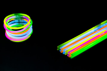 Colorful fluorescent light neon glow stick bracelet strap wristband on mirror reflection black background