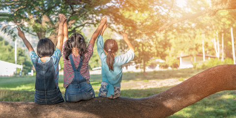 children friendship concept with happy girl kids in the park having fun sitting under tree shade pla