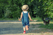 Little girl, dressed on dungarees  is chasing a hen on a country road