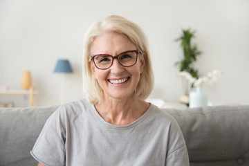 smiling middle aged mature grey haired woman looking at camera, happy old lady in glasses posing at 