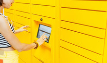 Woman Client Using Automated Self Service Post Terminal Machine Or Locker To Deposit The Parcel For Storage,