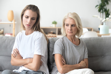 upset older mother in law and adult daughter sit back to back not talking after fight disagreement, 