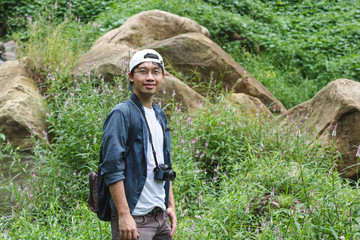 young asian adventure man looking at camera with nature green mountain background. travel lifestyle 