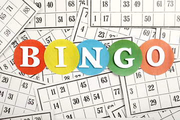 The word bingo made of wooden letters on bingo cards background.