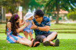 © TheVisualsYouNeed - young happy loving Asian Korean parents couple enjoying together sweet daughter baby girl sitting on grass at green city park in love and parenthood concept