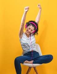Wall Mural - Young woman with headphones on a yellow background