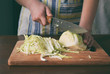 Woman cook sauerkraut or salad on wooden background. Step 1 - Chop Cabbage. Fermented preserved vegetables food concept.