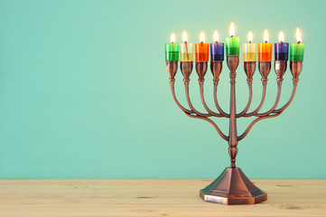 image of jewish holiday Hanukkah background with menorah (traditional candelabra) and colorful oil candles.