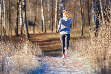 Rear view of young running woman in winter park