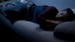 © motortion - Boy sleeping on couch in living room near laptop and earphones, gadget addiction