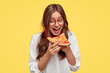 © wayhome.studio  - Hungry student opens mouth widely while sees delicious slice of pizza, wants to eat, dressed in white shirt, models against yellow background. Positive woman with junk food. People and eating