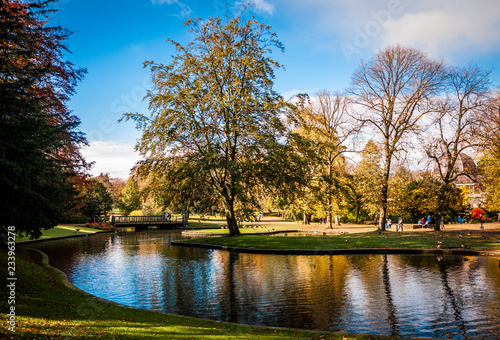 Fotografía Lovely view of Buxton Park in Autumn, showing the calm pond and beautiful autumnal trees as well as the stone architecture of the town