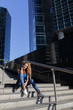 © oleg_chumakov - Beautiful girl sitting on the steps with her smartphone between skyscrapers