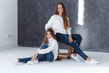 Stylish beautiful mother and a cute daughter with blue eyes in studio hugging and having fun. family, love concept