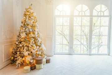 Classic christmas New Year decorated interior room New year tree. Christmas tree with gold decorations. Modern white classical style interior design apartment, large window. Christmas eve at home