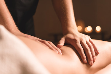 Wall Mural - Close-up male hands doing healing massage with oil to a young girl in a dark cosmetology office. Dark key