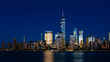 Night view of skyline of downtown Manhattan over Hudson River under dark blue sky, in New York City, USA