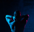 © Dmitry Lobanov - Neon light portrait of sexy smiling man muscular body looking up on dark